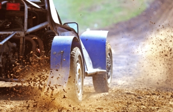 Racing car splashing in mud on a fast track