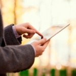 Man in tweed jacket using touchscreen tablet outside in woods