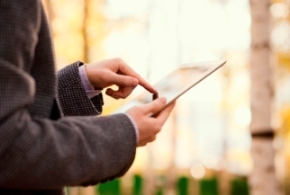 Man in tweed jacket using touchscreen tablet outside in woods