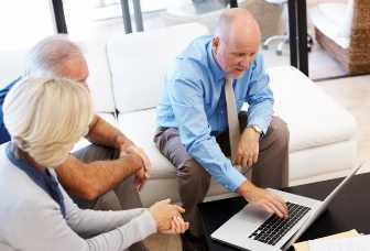 Sales and marketing executive selling to older couple on Apple computer